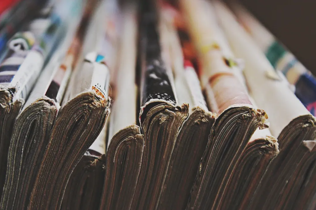Close-up of the worn spines and page edges of a row of old books and magazines.